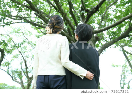 畢業典禮後，父母和孩子抬頭看著樹 73617231