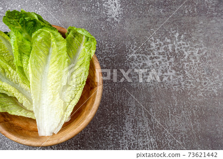 Fresh washed green salad in wooden bowl ready for cooking. Ingredients for cooking, vegetarian diet, healthy eating. Top view, space for text 73621442