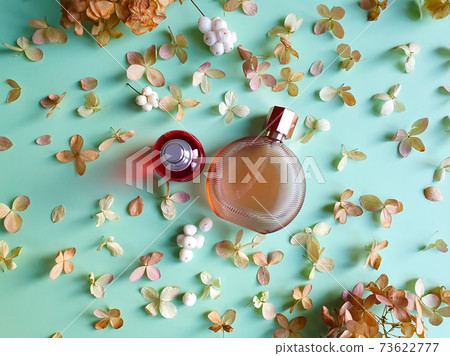 Two unbranded perfume bottles and dried hydrangea flowers on green background. Flatlay, mockup, top view. 73622777