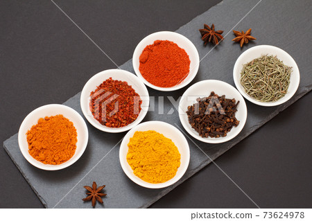 Various ground spices and herbs on stone cutting board. Various ground spices and herbs on stone cutting board. 73624978