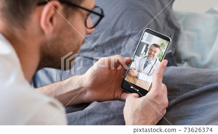 Young man having online consultation with doctor on smartphone, using telemedicine app on bed, panorama 73626374
