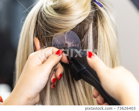 Blonde hair extensions procedure in beauty salon Blonde hair extensions procedure in beauty salon 73626403