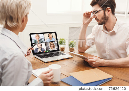 Businessman And Businesswoman At Laptop Communicating With Coworkers Online Indoors Businessman And Businesswoman At Laptop Communicating With Coworkers Online Indoors 73626420