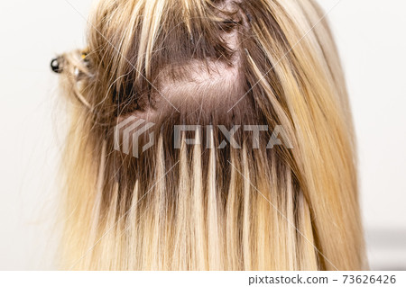 Blonde hair extensions procedure in beauty salon Blonde hair extensions procedure in beauty salon 73626426
