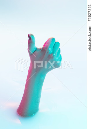 Close up female hand gesturing from the milk bath with soft glowing in neon light 73627261