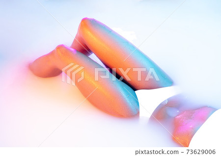 Close up female body in the milk bath with soft glowing in neon light Close up female body in the milk bath with soft glowing in neon light 73629006