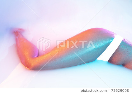 Close up female body in the milk bath with soft glowing in neon light 73629008