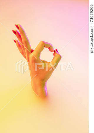 Close up female hand gesturing from the milk bath with soft glowing in neon light 73629266
