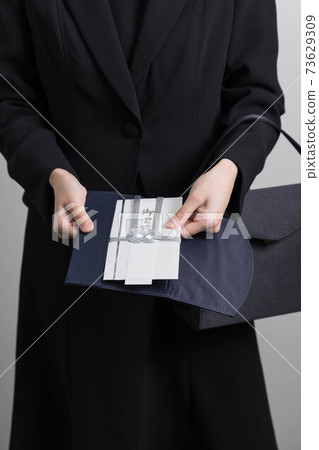 Hand of a young woman handing over the incense [Funeral] 73629309