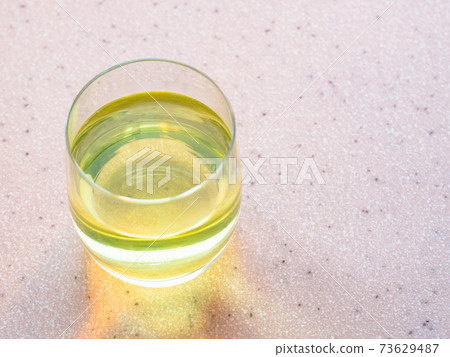 glass of water with yellow solution of vitamin 73629487