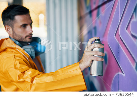 Street artist painting colorful graffiti on wall Street artist painting colorful graffiti on wall 73630544