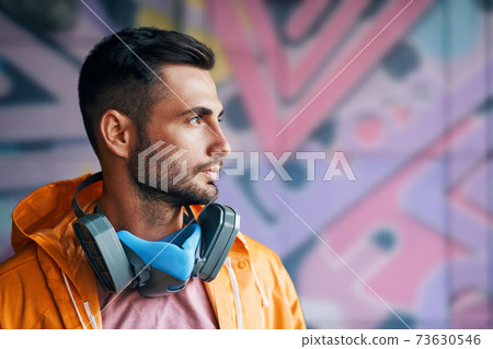 Portrait of handsome street artist staying on his graffiti painting background Portrait of handsome street artist staying on his graffiti painting background 73630546