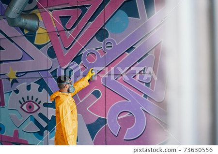 Street artist painting colorful graffiti on wall Street artist painting colorful graffiti on wall 73630556
