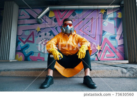Graffiti painter rest near the wall with his paintings looking to camera Graffiti painter rest near the wall with his paintings looking to camera 73630560