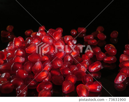 A bunch of pomegranate grains close up. Black background. A bunch of pomegranate grains close up. Black background. 73631900