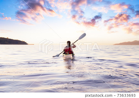 Woman on a sea kayak is paddling in the ocean 73633693