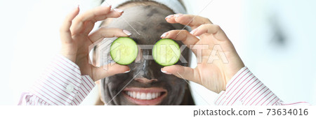 Laughing woman with a cosmetic mask on her face 73634016