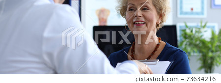 The doctor holds a folder and listens to a lady The doctor holds a folder and listens to a lady 73634216
