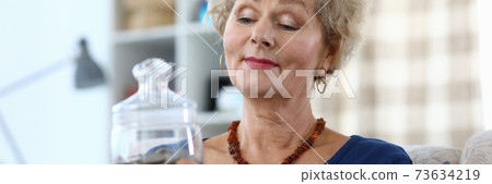Elderly woman holds a piggy bank with coins 73634219