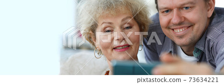 Adult son shows mother a photo in the phone 73634221