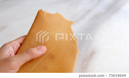Hand holding a variation of kuih kapit, an egg wafer snack popular in Indonesia, Malaysia, Brunei and Singapore. 73634644