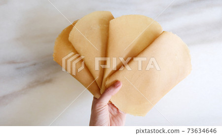 Hand holding many pieces of kuih kapit, an egg wafer snack popular in Indonesia, Malaysia, Brunei and Singapore. Hand holding many pieces of kuih kapit, an egg wafer snack popular in Indonesia, Malaysia, Brunei and Singapore. 73634646