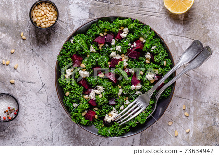 Healthy raw kale and beetroot salad with feta cheese and pine nut. 73634942