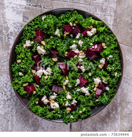 Healthy raw kale and beetroot salad with feta cheese and pine nut. 73634944