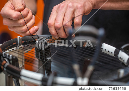 The process of stringing a tennis racket in a tennis shop The process of stringing a tennis racket in a tennis shop 73635666