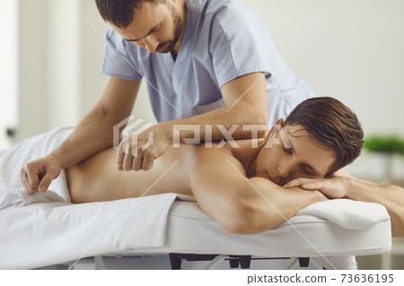 Relaxed young man enjoying remedial body massage in spa salon or wellness center 73636195