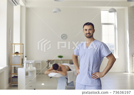 Young smiling confident man professional chiropractor masseur standing and looking at camera 73636197