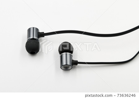 Black earphones lie on white background. Closeup Black earphones lie on white background. Closeup 73636246