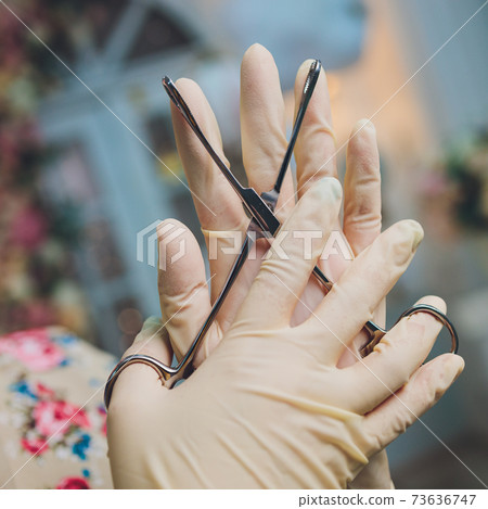 Doctor's hand in gloves and holding forceps. Doctor's hand in gloves and holding forceps. 73636747