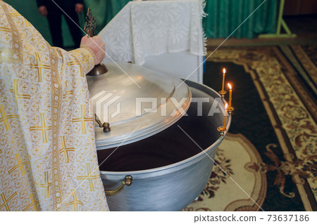 Water is poured into the font for bathing the baby in the church, religious traditions. Water is poured into the font for bathing the baby in the church, religious traditions. 73637186
