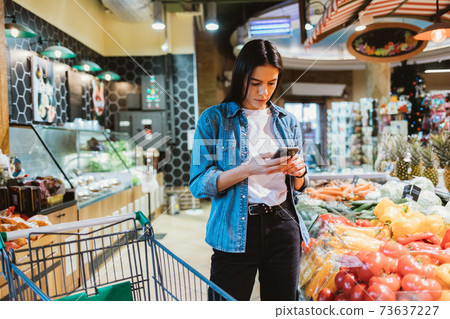 Young brunette woman looking at mobile phone Young brunette woman looking at mobile phone 73637227