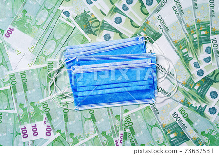 Protective face masks on background of Euro banknotes Protective face masks on background of Euro banknotes 73637531