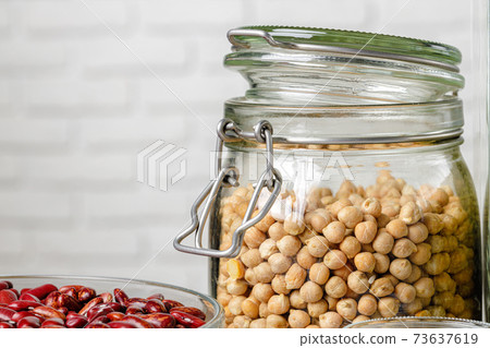 Raw cereals or beans in glass jars close up. Vegan and vegetarian food. Raw cereals or beans in glass jars close up. Vegan and vegetarian food. 73637619