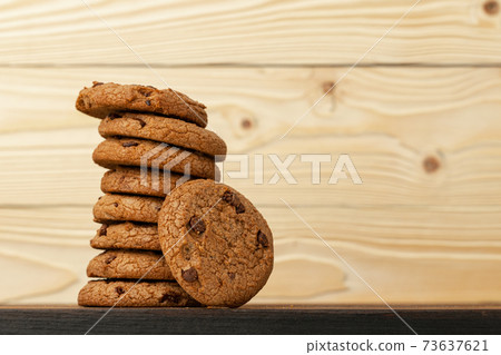 Heap of chocolate chip cookies against wooden background Heap of chocolate chip cookies against wooden background 73637621
