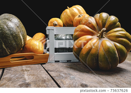 Pile of pumpkins in wooden box on wooden board Pile of pumpkins in wooden box on wooden board 73637626