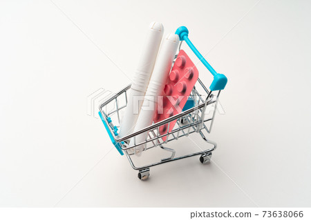 Female tampons and painkiller pills in toy shopping cart 73638066