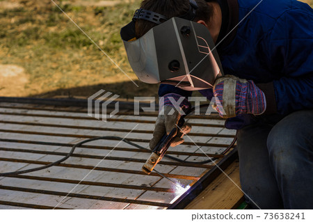 Metal welding, a worker in a protective mask against bright light and sparks, a robot on the street. Metal welding, a worker in a protective mask against bright light and sparks, a robot on the street. 73638241