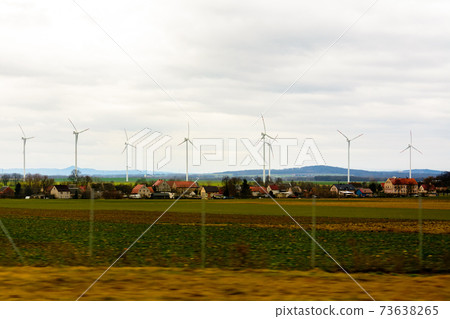 Windmills far in field in countryside of Poland from car window 73638265