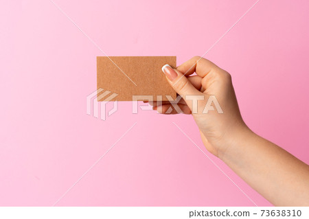 Woman hand showing blank business card on pink background. Woman hand showing blank business card on pink background. 73638310