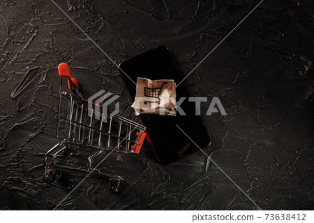 Damaged paper box on a screen of smartphone and shopping cart. Online shopping, service and delivery concept Damaged paper box on a screen of smartphone and shopping cart. Online shopping, service and delivery concept 73638412