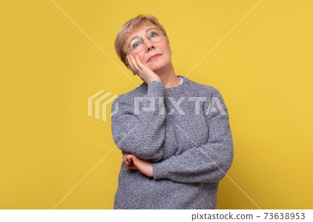 Thinking senior woman in glasses thinking trying to make a decision. Thinking senior woman in glasses thinking trying to make a decision. 73638953