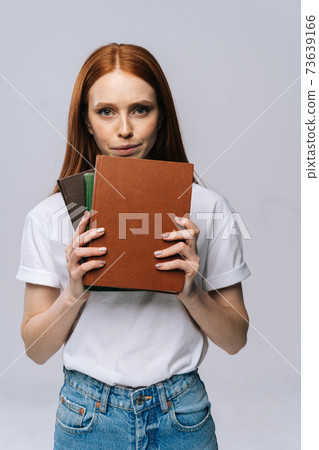 Upset sad young woman college student holding book and looking at camera on isolated background. Upset sad young woman college student holding book and looking at camera on isolated background. 73639166