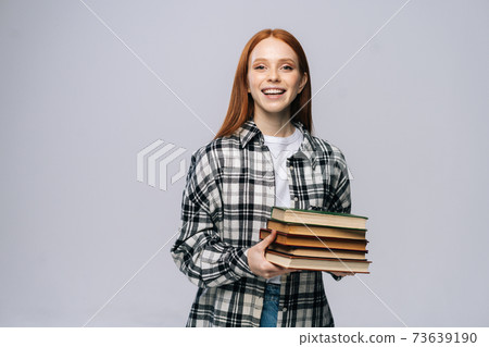 Cheerful smiling young woman college student holding book and looking at camera. 73639190