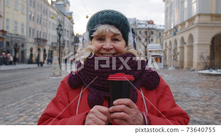 Portrait of senior woman tourist smiling, looking at camera in winter city center of Lviv, Ukraine Portrait of senior woman tourist smiling, looking at camera in winter city center of Lviv, Ukraine 73640755
