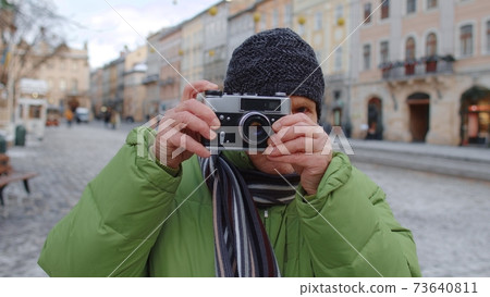 Senior man taking pictures with photo camera, using retro device outdoors in winter city center Senior man taking pictures with photo camera, using retro device outdoors in winter city center 73640811