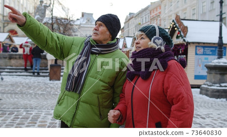 Senior elderly couple tourists grandmother grandfather staying in winter city center Lviv, Ukraine 73640830